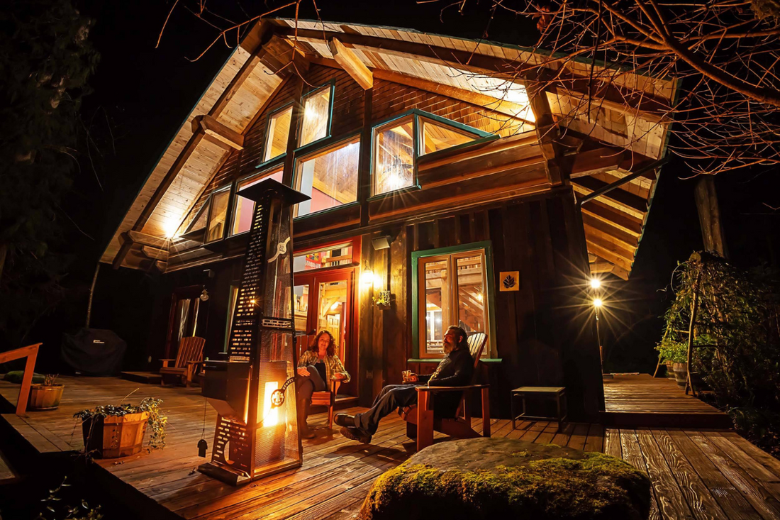 Two people sitting out front of their cabin, enjoying the warmth of a pellet patio heater